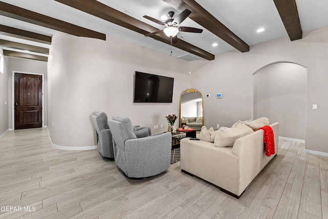 living area with light wood finished floors, baseboards, arched walkways, ceiling fan, and beamed ceiling