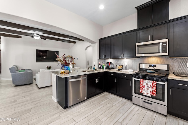 kitchen with appliances with stainless steel finishes, dark cabinetry, a sink, and tasteful backsplash