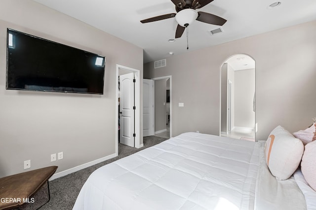 carpeted bedroom with baseboards, visible vents, arched walkways, and a ceiling fan