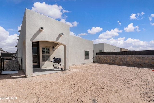 rear view of house featuring fence, a patio, and stucco siding