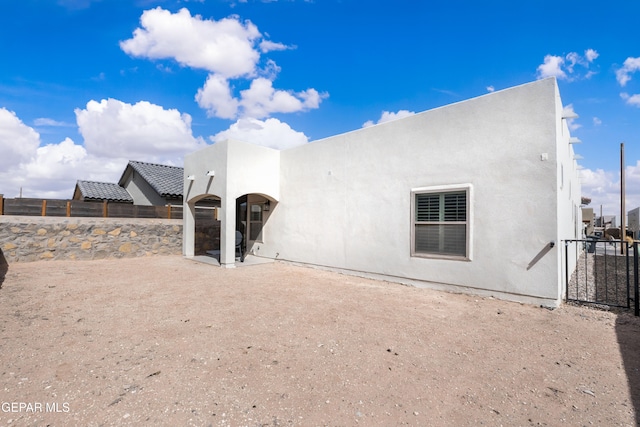 rear view of house featuring fence and stucco siding