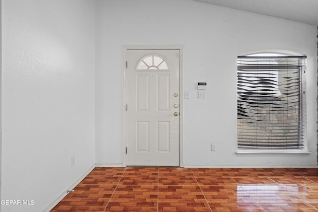 foyer featuring lofted ceiling and baseboards