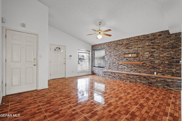 unfurnished living room with a textured ceiling, ceiling fan, and high vaulted ceiling