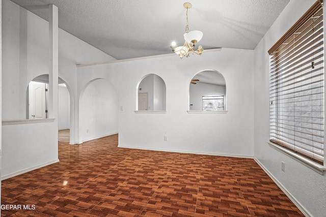 empty room featuring baseboards, arched walkways, vaulted ceiling, a textured ceiling, and a notable chandelier