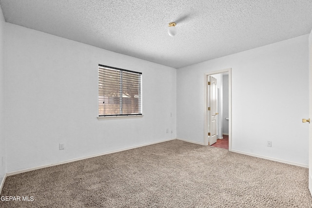 spare room with carpet floors, baseboards, and a textured ceiling