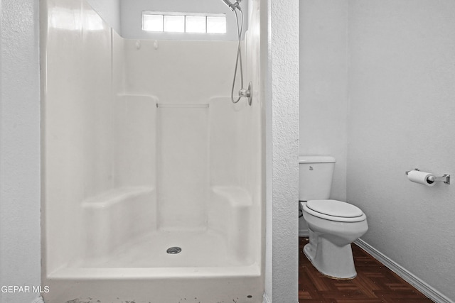 bathroom featuring a stall shower, baseboards, and toilet