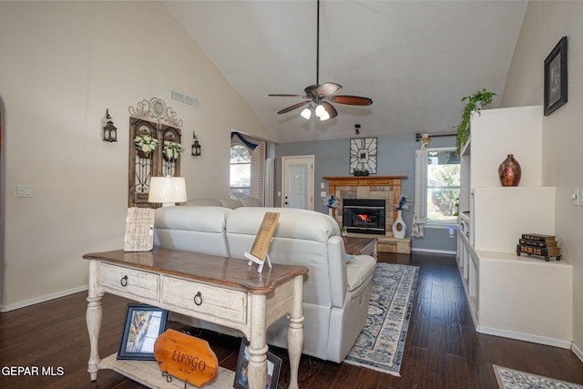 living area featuring baseboards, visible vents, dark wood-style flooring, and a stone fireplace