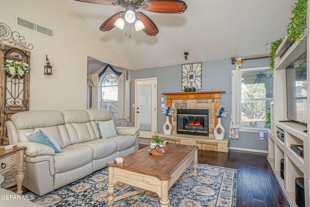 living room featuring ceiling fan, dark wood finished floors, visible vents, vaulted ceiling, and a glass covered fireplace