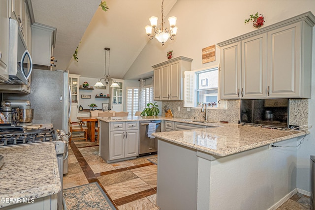 kitchen featuring tasteful backsplash, appliances with stainless steel finishes, a peninsula, a chandelier, and a sink