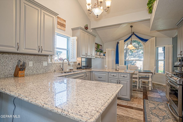 kitchen featuring lofted ceiling, a peninsula, a sink, tasteful backsplash, and gas range