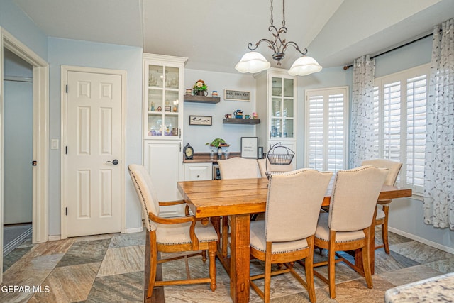 dining room with vaulted ceiling, a notable chandelier, and baseboards