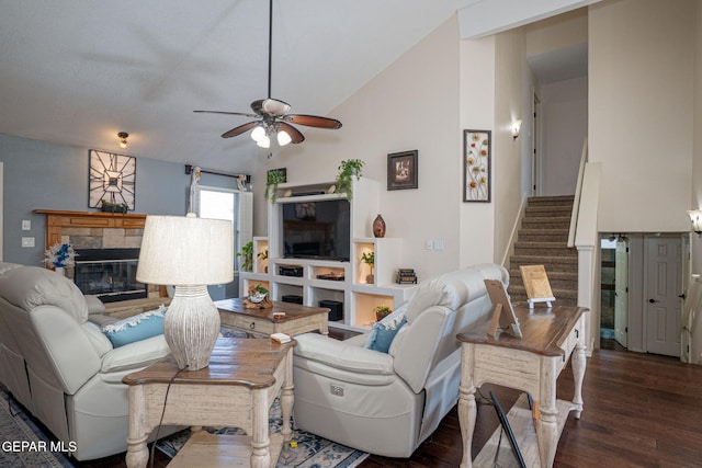 living room featuring stairs, vaulted ceiling, wood finished floors, and a stone fireplace