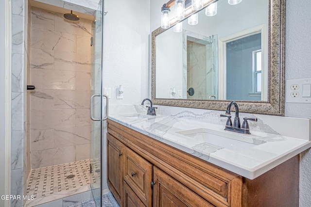 full bathroom with double vanity, a stall shower, and a sink