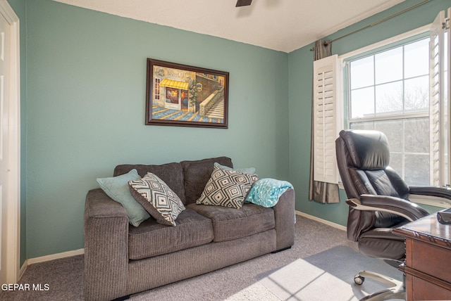 carpeted office space featuring ceiling fan and baseboards