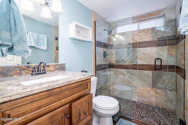 full bath featuring toilet, a stall shower, a notable chandelier, and vanity