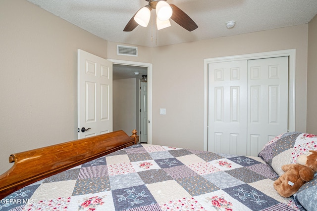 bedroom featuring ceiling fan, a closet, a textured ceiling, and visible vents