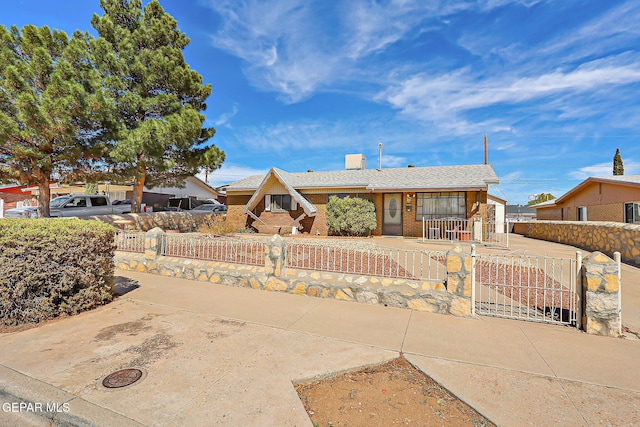 view of front of house featuring concrete driveway, brick siding, a fenced front yard, and a gate