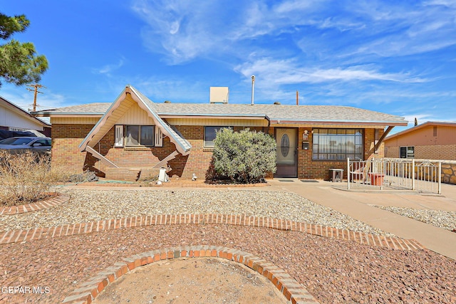 view of front of property with a shingled roof and brick siding