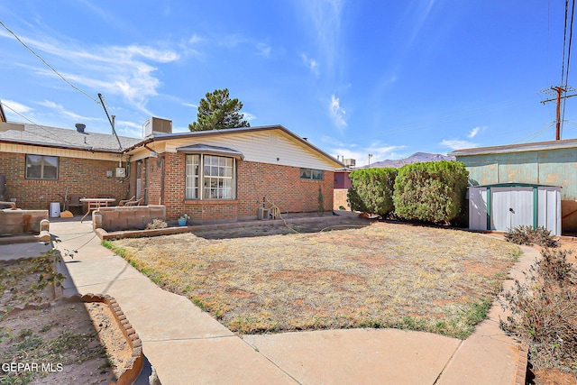 view of front of house with a shed, an outdoor structure, a patio, and brick siding