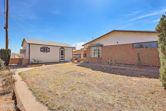 back of property with fence, an outbuilding, and brick siding