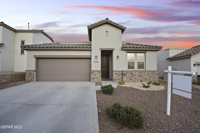 view of front of house featuring stone siding, an attached garage, and stucco siding