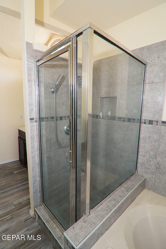 full bathroom featuring wood finished floors and a shower stall