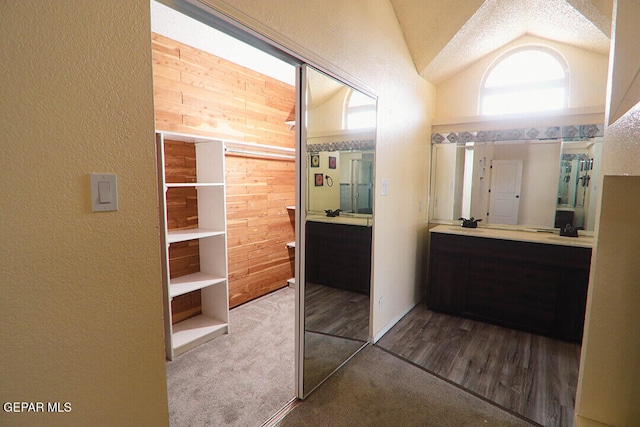 full bath featuring lofted ceiling, a textured wall, and vanity