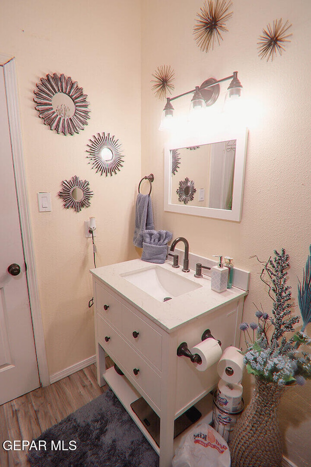 bathroom featuring vanity, baseboards, and wood finished floors