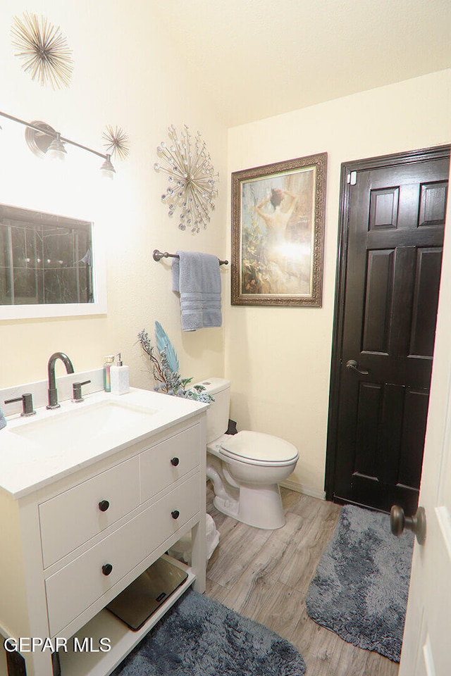 bathroom with toilet, wood finished floors, and vanity