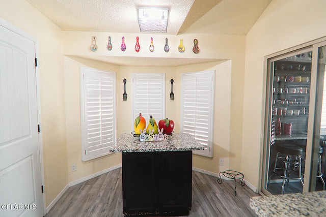 interior space with a textured ceiling, baseboards, and wood finished floors