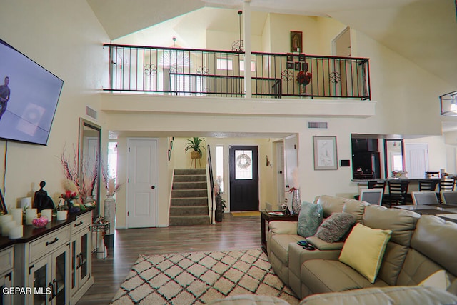 living room with stairs, high vaulted ceiling, dark wood-type flooring, and visible vents