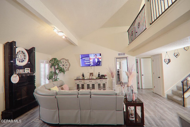 living room with visible vents, stairway, wood finished floors, and beamed ceiling