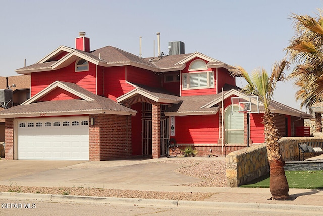 view of front of house featuring driveway, a chimney, an attached garage, central AC, and brick siding