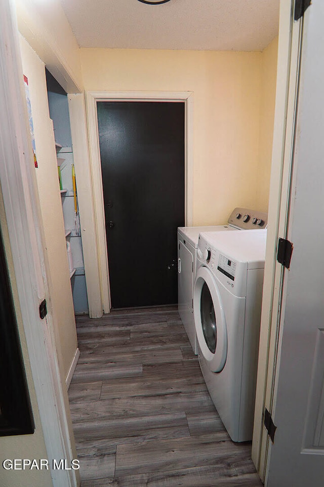 laundry area featuring laundry area, wood finished floors, and washing machine and clothes dryer