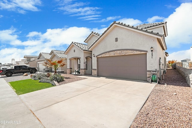 mediterranean / spanish-style house with fence, a tile roof, concrete driveway, stucco siding, and an attached garage