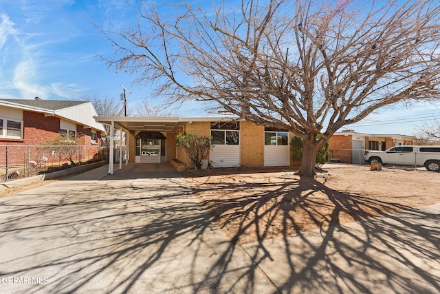 single story home featuring concrete driveway, brick siding, and fence