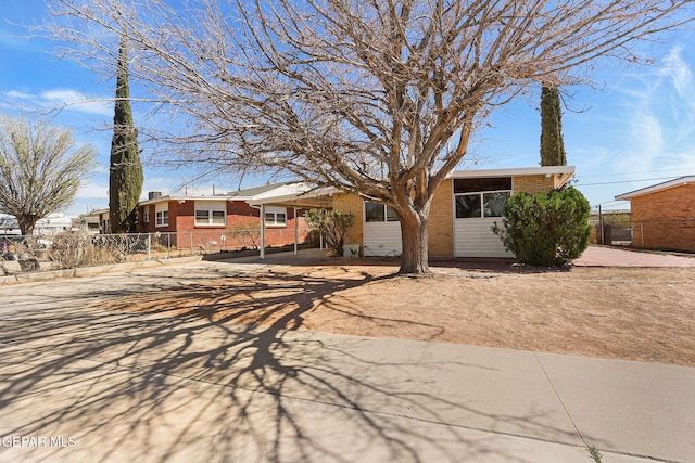 single story home featuring concrete driveway, brick siding, and fence