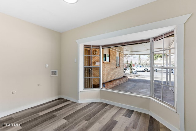 unfurnished dining area with a sunroom, baseboards, and wood finished floors