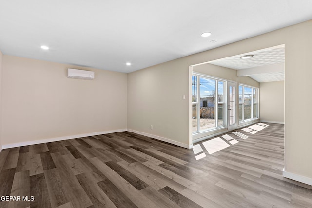 spare room with recessed lighting, an AC wall unit, baseboards, and wood finished floors