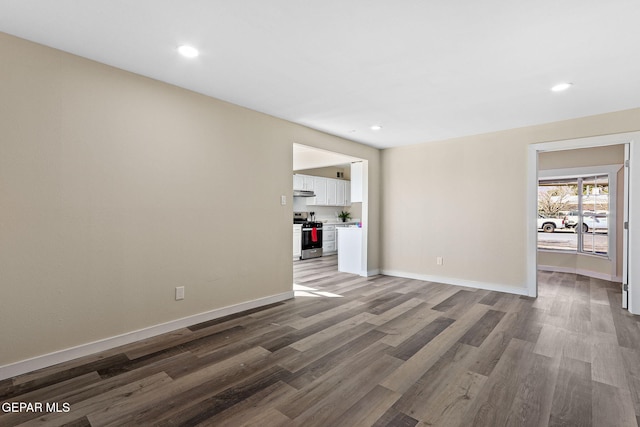 spare room with baseboards, wood finished floors, and recessed lighting