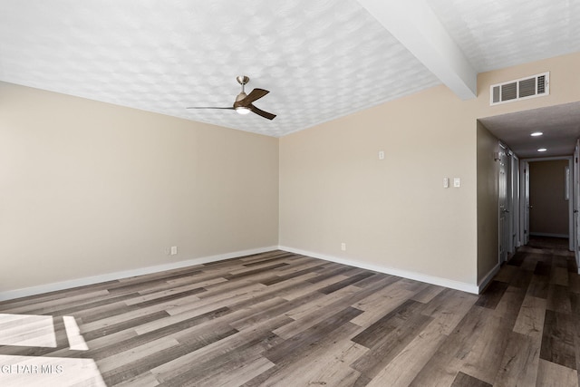 spare room with a textured ceiling, wood finished floors, visible vents, and baseboards