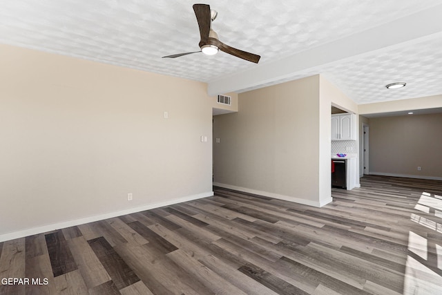 empty room with visible vents, a ceiling fan, a textured ceiling, wood finished floors, and baseboards