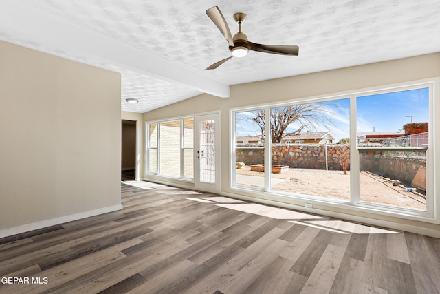 spare room with a textured ceiling, baseboards, wood finished floors, and vaulted ceiling with beams