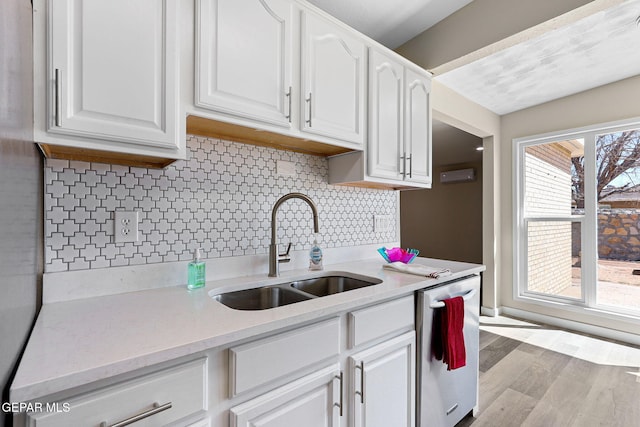 kitchen featuring white cabinetry, a sink, stainless steel dishwasher, and wood finished floors