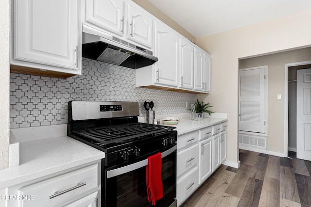 kitchen with under cabinet range hood, wood finished floors, white cabinetry, stainless steel gas range, and decorative backsplash