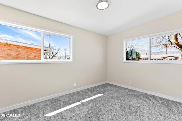 carpeted spare room with vaulted ceiling and baseboards