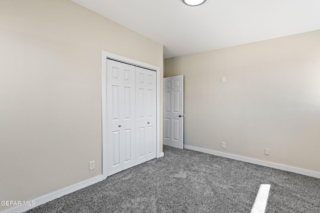 unfurnished bedroom with a closet, carpet, and baseboards