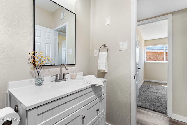 bathroom featuring visible vents, baseboards, wood finished floors, and vanity