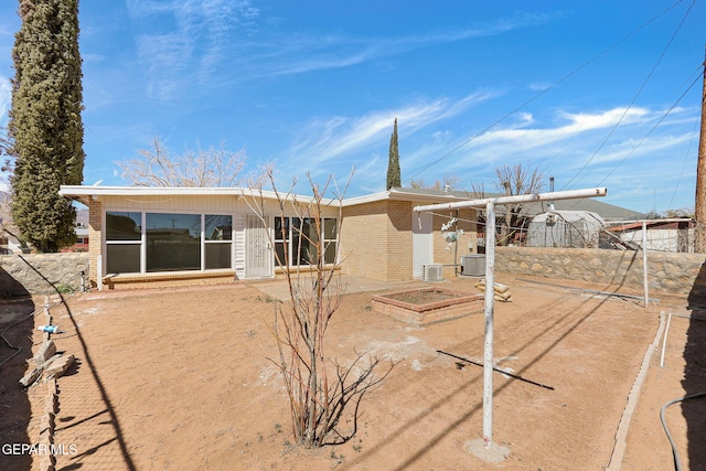 rear view of property with brick siding, a vegetable garden, fence, and central AC unit