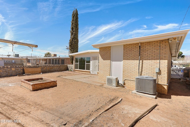 rear view of house with brick siding, ac unit, cooling unit, and fence